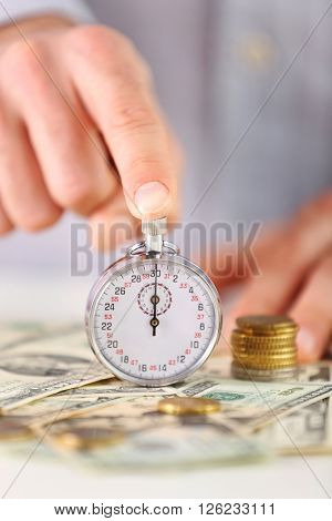 Time is money concept. Stopwatch  on the table with money, close up