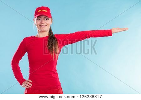 Portrait of happy lifeguard woman girl in red cap with ratownik sign pointing dircetion on blue. Accident prevention rescue.