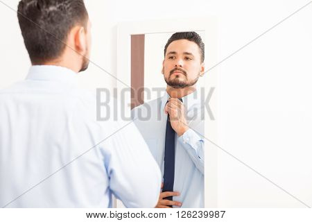 Hispanic Young Man Putting On A Necktie