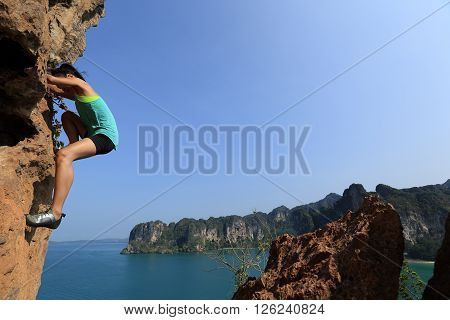 free solo woman rock climber climbing at seaside mountain rock wall