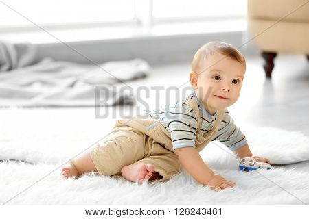 Little baby boy with a toy sitting on the floor at home