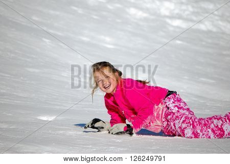 Portrait of adorable girl with blue eyes wearing a pink coat out in the snow with copyspace.