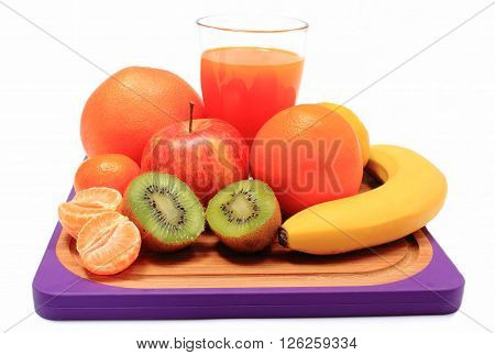 Fresh ripe natural fruits and glass of juice on cutting board apple grapefruit banana lemon orange kiwi concept for healthy nutrition