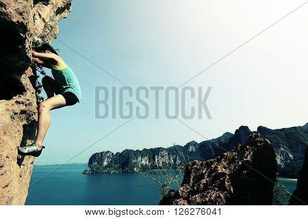 free solo woman rock climber climbing at seaside mountain rock wall