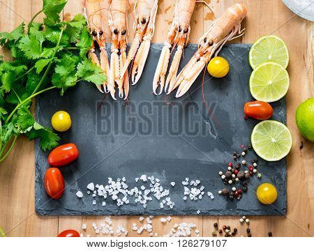 Fresh scampi, lemon lime, white salt and cherry tomatos around the black rock