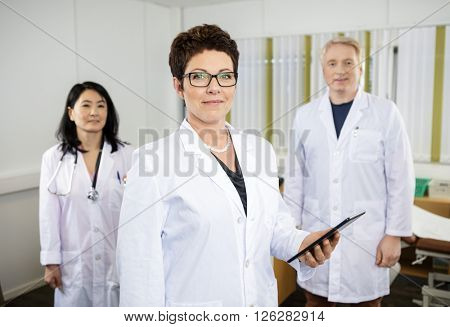 Female Doctor Holding Digital Tablet While Standing With Colleag