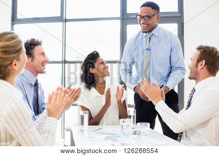 Business team applauding a colleague in meeting