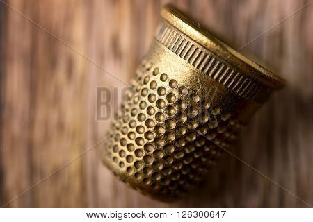 macro of brass thimble on wood for sewing