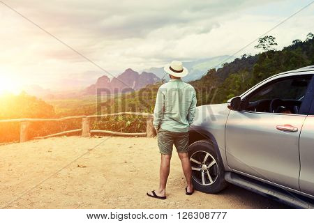 Back view of a man is thinking about this amazing world while is standing on a mountain against jungle view.