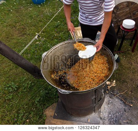 Man cooking traditional Asian meal in large old style iron pan
