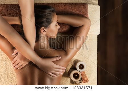 The beautiful girl has relaxing massage. Spa treatment. Candle setup