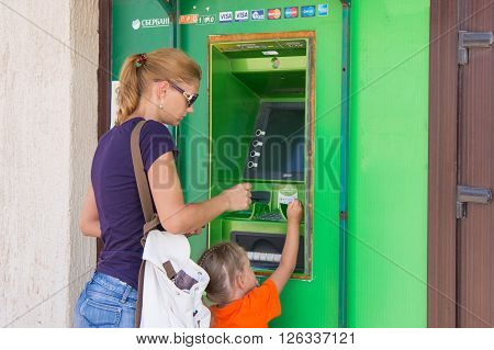 Anapa Russia - September 20 2015: A young girl with the child to withdraw money from the ATM Sberbank