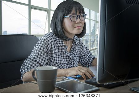 45s years woman working in front of computer monitor office life theme