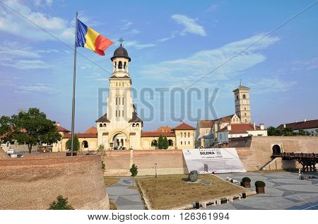 ALBA IULIA, ROMANIA - AUGUST 11, 2015: the Romanian flag waving on the Coronation Cathedral in Carolina Citadel of Alba Iulia