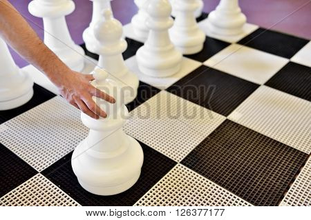 Hand moving a pawn on a giant chess game