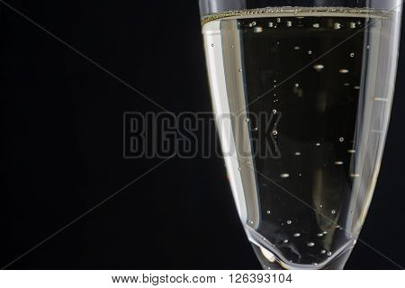 a glass of white wine on a black background