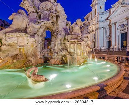 Illuminated at night the fontana del Moro (the Moor Fountain) on Piazza Navona on the Sant'Agnese in Agone church background, Rome, Italy