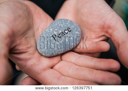 Hands holding pebble stones with the word peace