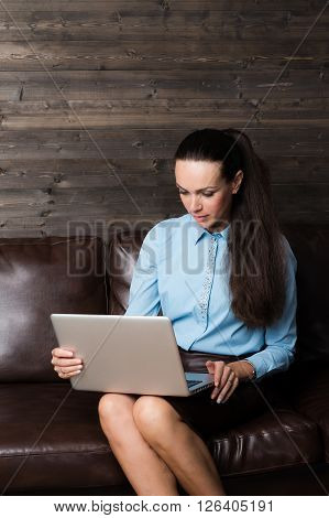 Business lady looking to the laptop on the brown wooden background for use e.g. in collages, presentation