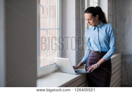 Business lady looking to the laptop near the bright windows