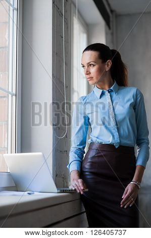Business lady looking to the bright window bright office background