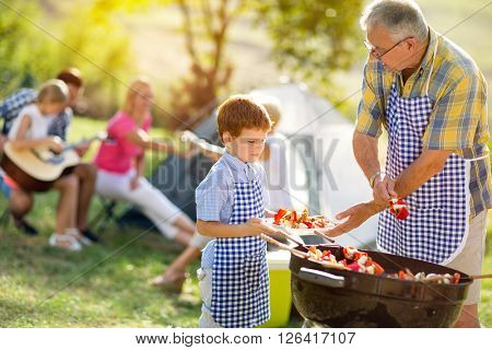 grandfather giving grandson grillied meat for dinner