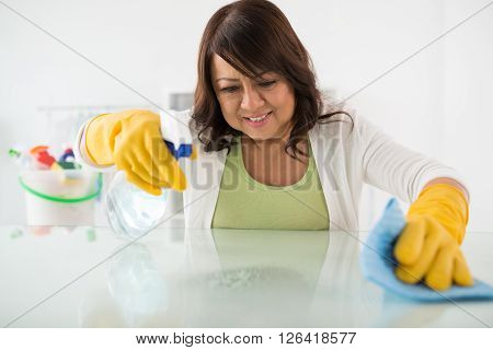 Housewife cleaning surface of the table with disinfectant