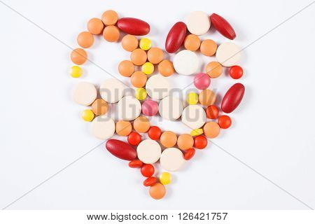 Heart shaped colorful medical pills capsules or supplements for therapy on white background concept of treatment and health care