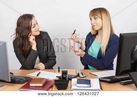 Office Employee Demonstrates Lipstick Colleague At The Desk