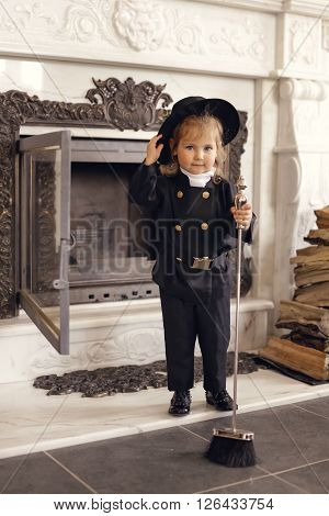 Girl as a chimney sweep against fireplace. Lucky New Year's Eve and New Year.