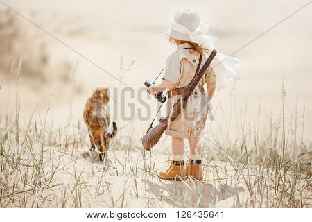 Concept of travel and fascinating adventures. hild in suit of treasures seeker like Indiana Jones in the desert whit wild cat similar to tiger