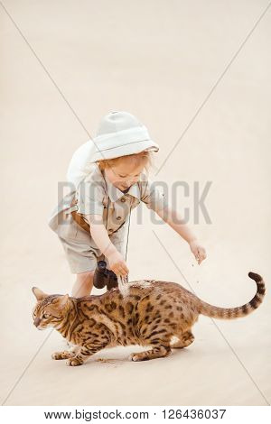 Concept of travel and fascinating adventures. hild in suit of treasures seeker like Indiana Jones in the desert whit wild cat similar to tiger