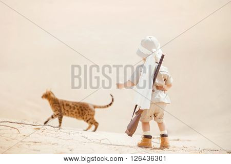 Concept of travel and fascinating adventures. hild in suit of treasures seeker like Indiana Jones in the desert whit wild cat similar to tiger