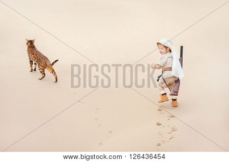 Concept of travel and fascinating adventures. hild in suit of treasures seeker like Indiana Jones in the desert whit wild cat similar to tiger