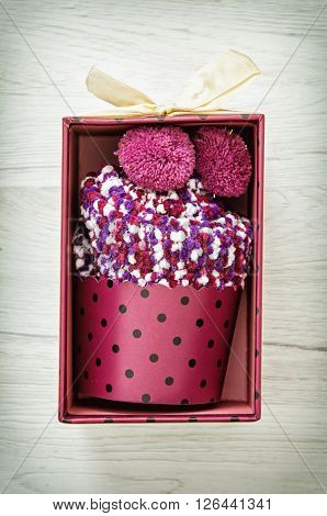 New knitted socks in the shape of cupcake on the wooden background. Beauty and fashion.