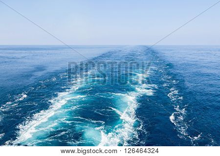 Blue wake of cargo vessel on the sea water surface.