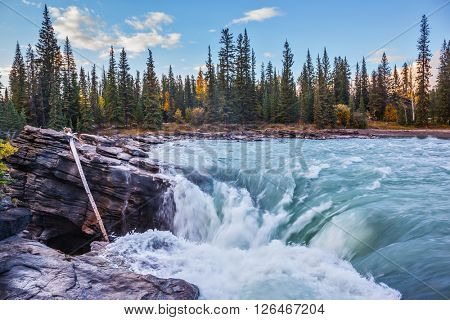 Scenic and powerful Athabasca Falls. Sunset  illuminates the surrounding mountains. Canada, Jasper National Park