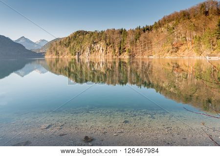Crystal clear water reflection in Hohenschwangau lake with bavarian alps in Germany