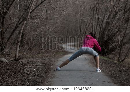 Beautiful young woman doing stretching exercises before running in the park