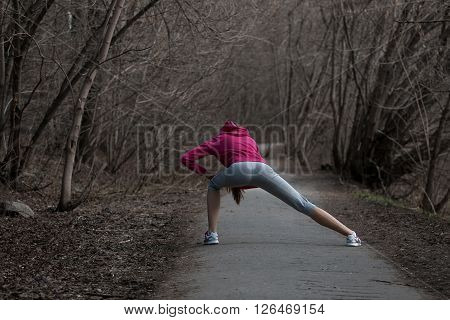 Beautiful young woman doing stretching exercises before running in the park