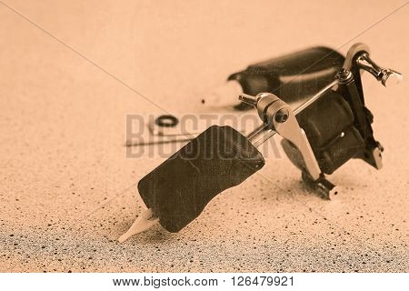 Machine for tattoo and bottle with black ink, on grey background. Retro stylization