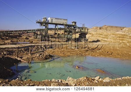 Coal mining equipment by a green water pond