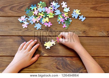 Child holding puzzles in hands. A set of jigsaw puzzles on wooden table