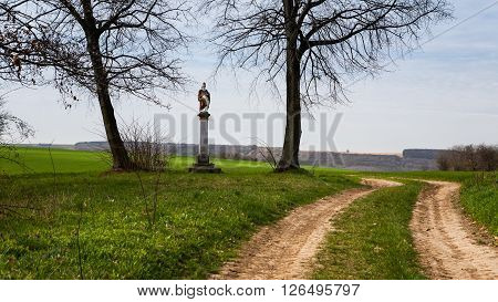 St. Urban statue between two lime trees near a country road