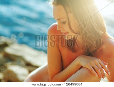Portrait of a young beautiful girl in sunset light, with water in the background