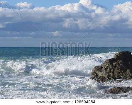 Stormy sea and sailboat along Tuscany coastline in Livorno Italy