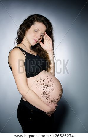 Pregnant girl with henna tattoo on her belly. Studio