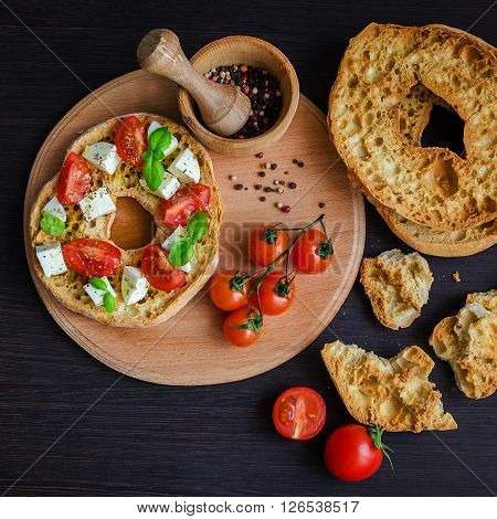 Italian appetizer Friselle. Italian dried bread Friselle on wooden board with tomatoes cherry, basil and peppercorns. Italian food. Healthy vegetarian food. Antipasti concept.