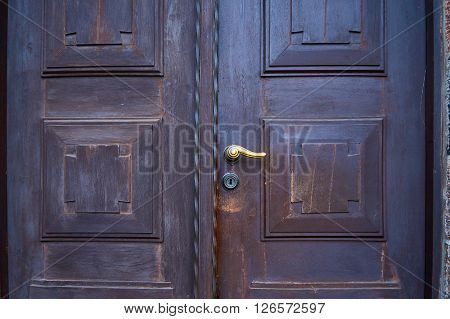 Old wooden church door with brass handle with lock