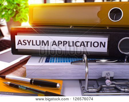 Black Ring Binder with Inscription Asylum Application on Background of Working Table with Office Supplies and Laptop. Asylum Application Business Concept on Blurred Background. 3D Render.